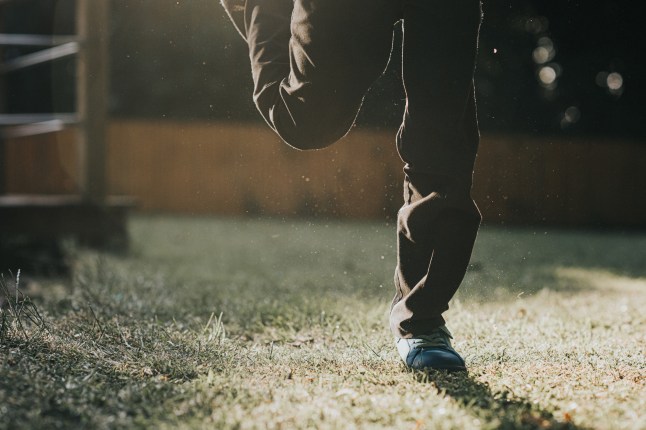 A child wearing school trousers and trainers plays outside