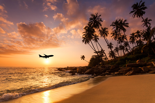 Beach at sunset and a flying plane. Summer vacation on tropical resort