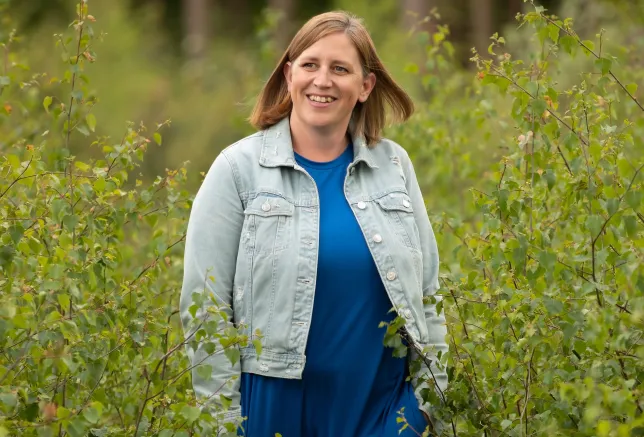 Kirsty Ketley smiles in front of a green outdoor landscape