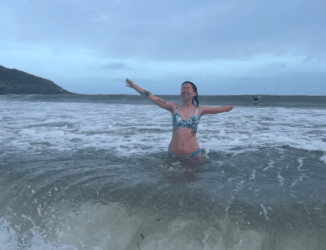 Emily in the sea, with her arms in the air