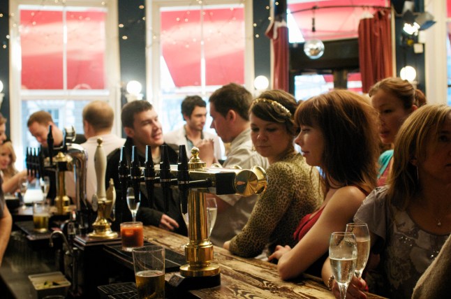 People stood along a bar ordering drinks in a pub